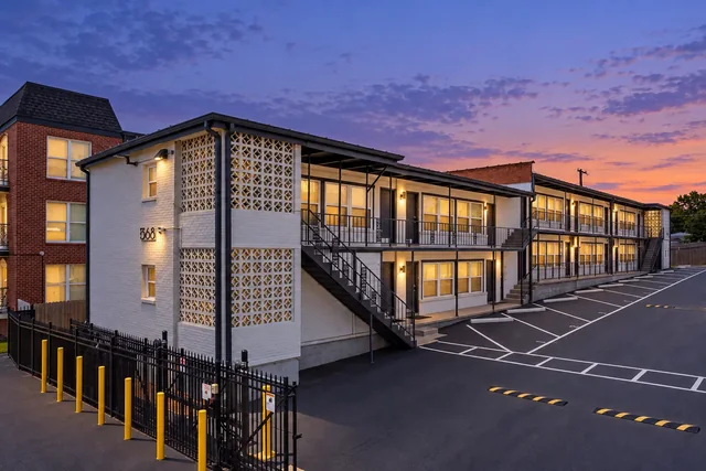 White brick Crescendo apartment building beside marked parking spaces and a black metal gate