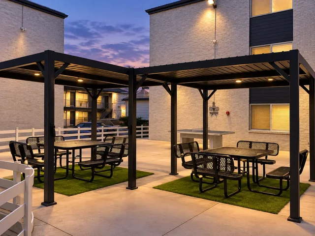 Twilight view of two black gazebos with picnic seating in the Crescendo courtyard